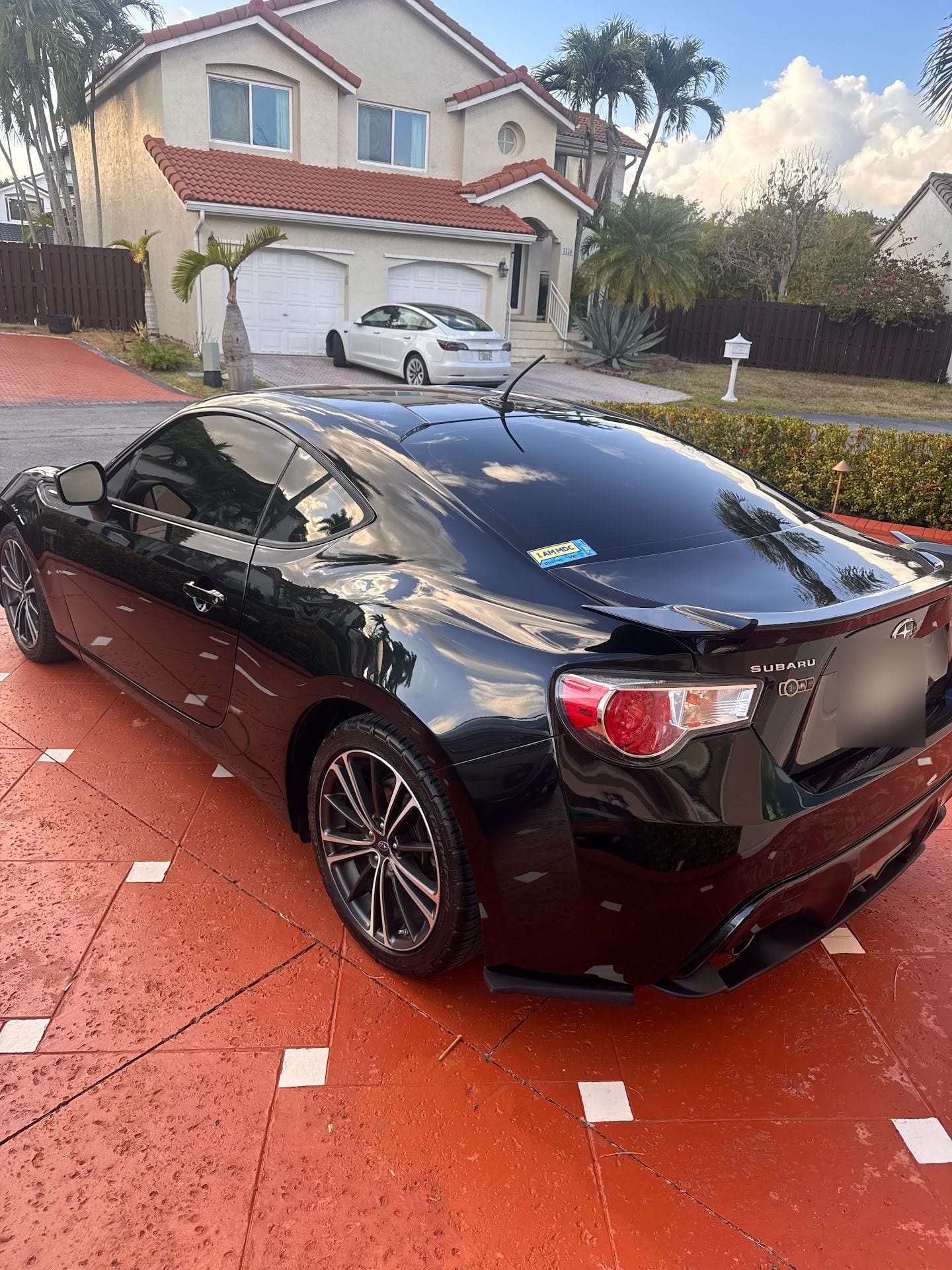 Rear three-quarter view of the repaired black Subaru BRZ in a driveway