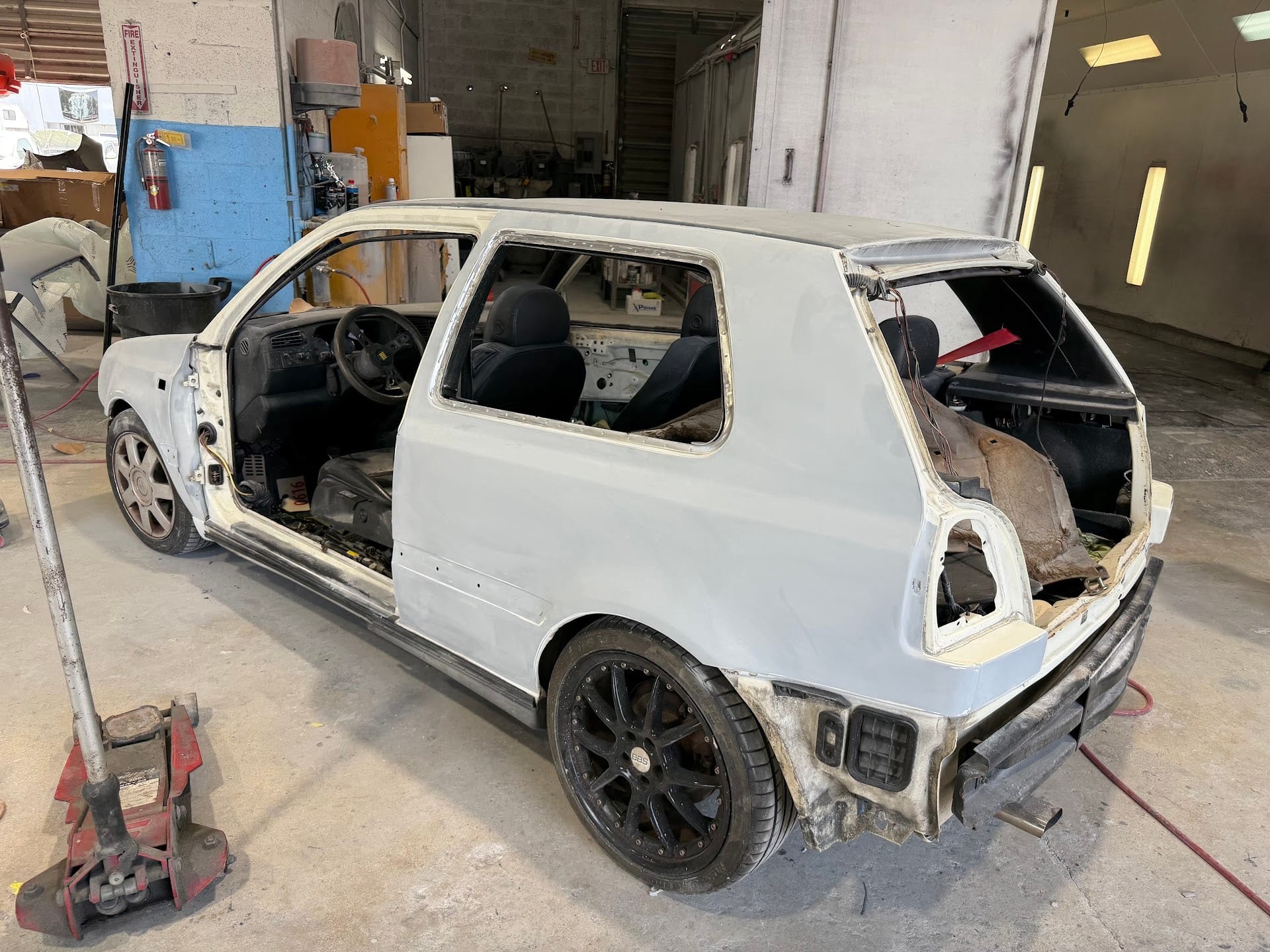 Rear of the stripped VW Golf in primer inside the bay