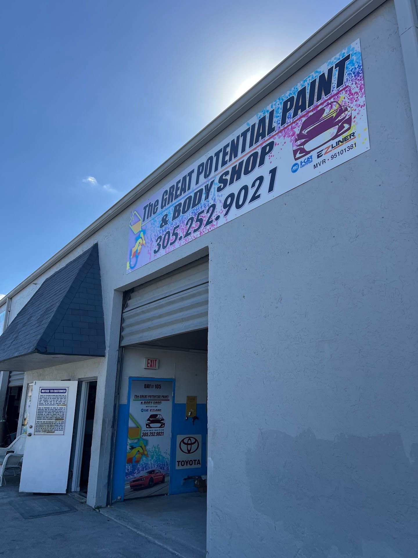 The shop's bay door under the rainbow sign reading The Great Potential Paint & Body Shop, 305.252.9021